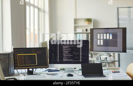 Background image of several computer screens with code lines on desk in IT programmers office, copy space Stock Photo