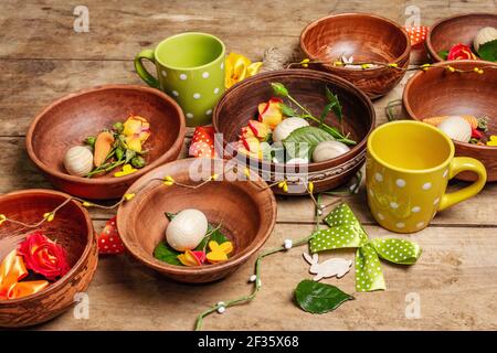 Easter ceramic bowls with eggs, bunnies, and fresh roses on a vintage table. Collection of traditional dishes with fresh flowers, cups, and ribbons. F Stock Photo
