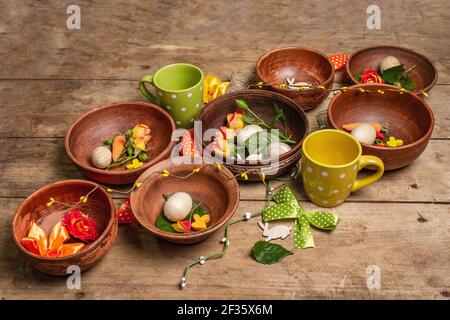Easter ceramic bowls with eggs, bunnies, and fresh roses on a vintage table. Collection of traditional dishes with fresh flowers, cups, and ribbons. F Stock Photo