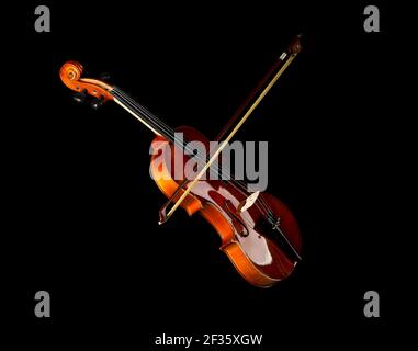 Brown wooden fiddle or violin, classic musical instrument, with bow isolated over black background, selective focus Stock Photo