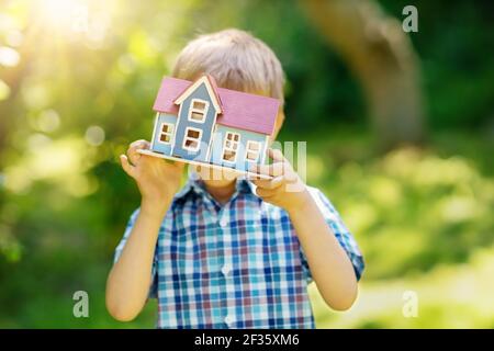 Little child holding in his hands model of the blue wooden house Stock Photo