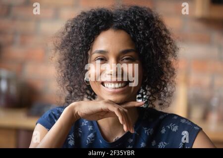 Laughing millennial black woman looking at camera flirtatiously touching chin Stock Photo