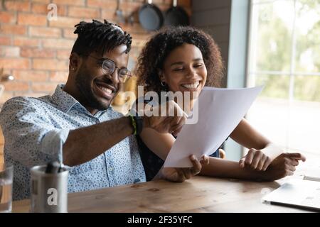 Excited black couple read paper contract satisfied with good conditions Stock Photo