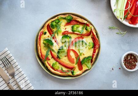 omelette or frittata with broccoli, bell pepper and arugula on a gray stone background. traditional italian dish. top view, horizontal image, copy Stock Photo