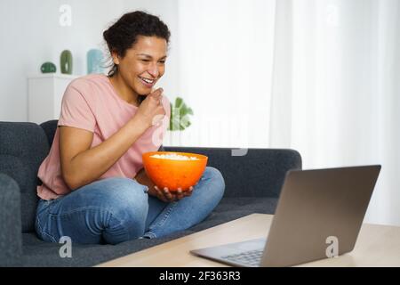 Happy black woman is watching a streaming movie at home