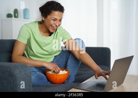 Happy black woman is watching a streaming movie at home