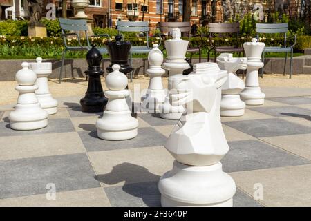 Empty park with big chess figures and empty chairs on background.Nobody playing in real games. Stock Photo
