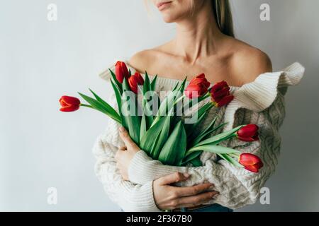 A young woman holds a gorgeous bouquet of red tulips in her hands. Stock Photo