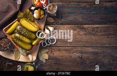 Pickled cucumbers in a wooden plate on a cutting board with spices. Homemade pickles. Stock Photo