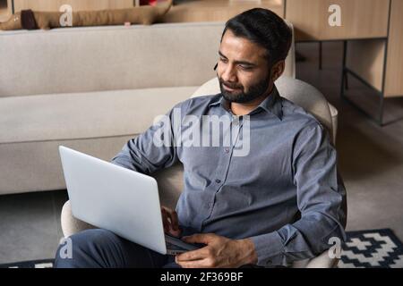 Serious indian businessman working on laptop computer from home office. Stock Photo