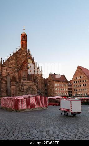 Red and white striped market tents cover booths on the Hauptmarkt, in front of the Frauenkirche in Nuremberg, Germany. Stock Photo
