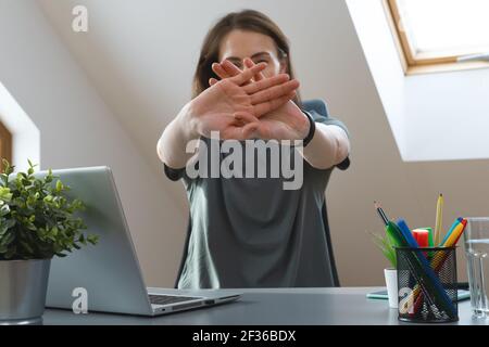 Working from home exercise. Young woman stretching hands while sitting at desk. Healthy living during office hours. Stock Photo