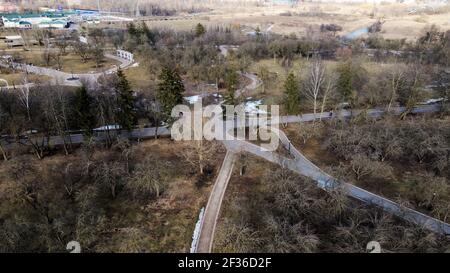 Flight over the city park. A pedestrian alley is visible below. High-rise city houses in the distance. Stock Photo