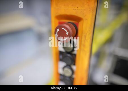 Shallow depth of field (selective focus) image with an emergency stop button on a control panel from a factory. Stock Photo