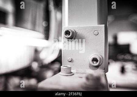 Shallow depth of field (selective focus) image with details of industrial metallic nuts and bolts in a heavy factory. Stock Photo