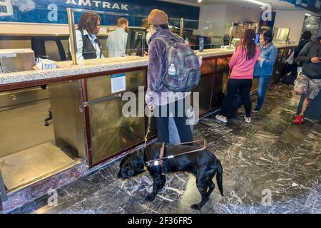 Washington DC,Union Station,railroad train terminal Amtrak ticket window,Black man disabled passenger rider service dog interior inside,buying counter Stock Photo