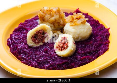 potato dumplings filled with smoked meat with fried onion on red cabbage Stock Photo