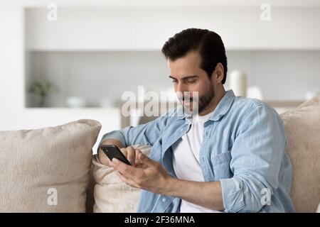 Pensive man relax on sofa using smartphone Stock Photo