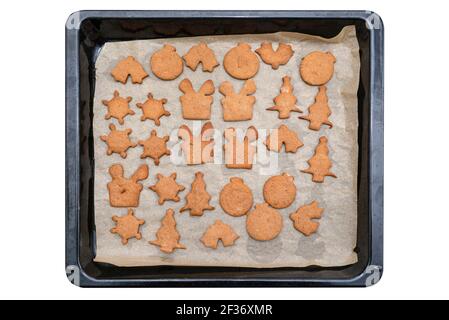 Baked gingerbread cookies in various shapes without decorations, lying on baking paper, isolated on white background witha a clipping path, top view. Stock Photo