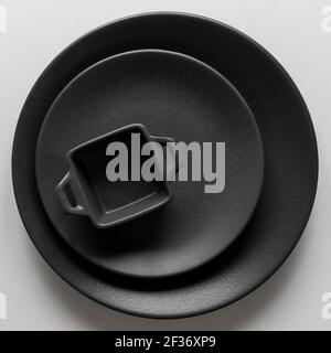 Top view of black empty plates and small baking dish on white background Stock Photo