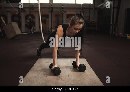 Female athlete doing push ups on dumbbells Stock Photo