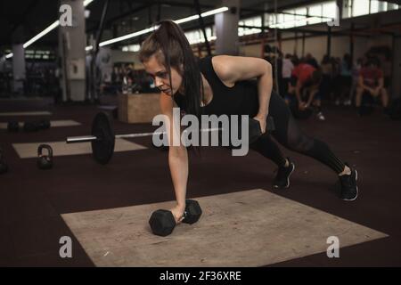 Athletic woman exercising with dumbbells, doing push ups Stock Photo