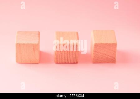 Abstract geometric real wooden cube with surreal layout on pink background Stock Photo