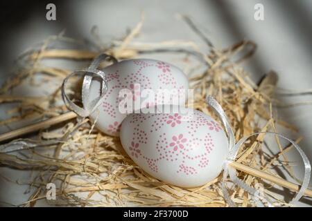 Two white eggs in the hay, beautiful background with shadows Stock Photo