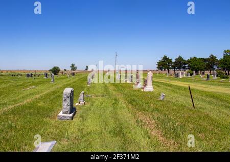 American country cemetary out on the plains with some graves decorated for Memorial Day and farmland in the distance Stock Photo