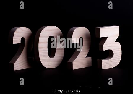 2023 year large wooden numbers overlapping. Hardwood characters on a black background Stock Photo