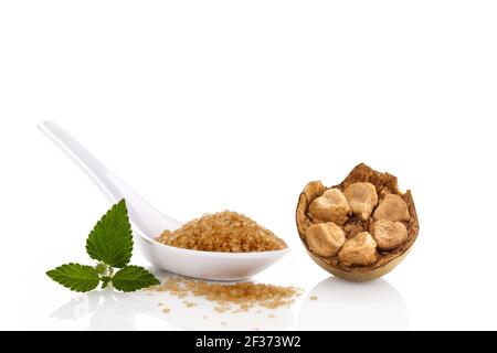 Heap of brown cane crystallized sugar in white spoon and monk fruit, luo han guo isolated on white background. Stock Photo