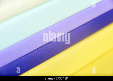 Geometric colorful background, close-up oblique view of a pile of books filling the frame. Diagonal colored stripes. Macro image with shallow depth of Stock Photo