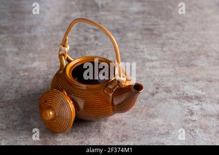 A brown teapot with a bamboo handle and an open lid on a stone countertop. copyspice Stock Photo