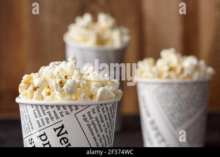 A bucket of popcorn, top-view, warm colors, light brown wooden background, daylight macro close-up Stock Photo