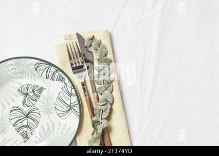 Festive table setting. Plates and cutlery with yellow napkin on white background. Beautiful flat lay arrangement. Stock Photo
