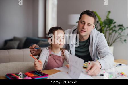Father helping daugther with homework indoors at home, distance learning. Stock Photo