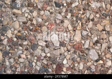 background of small multi-colored pebble stones in concrete, cement wall with decorative splashes Stock Photo