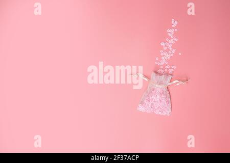 Organza bags on pink background texture with beautiful flowers coming out, white Daisies, Spring,Mothers Day, Love, Holiday Minimal concept. Flat lay Stock Photo