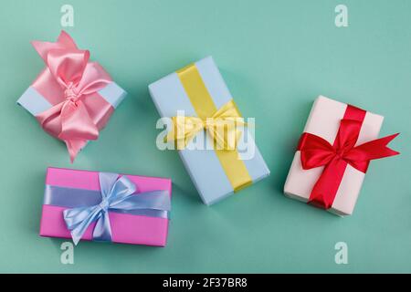 Different gift boxes with red, yellow. and blue bows on turquoise color background. Mother's day or minimalism concept to sale company Stock Photo