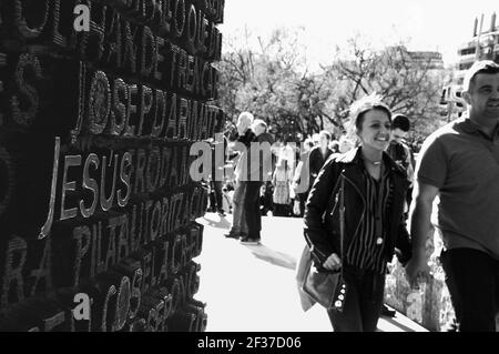 Happy young couple of tourists entering to Sagrada Familia basilica through bronze Gospel door, with word Jesus on it. Barcelona, Spain. Black white Stock Photo