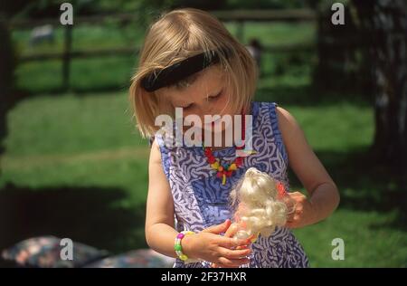 Young girl playing with Barbie doll, in garden, Winkfield, Berkshire, England, United Kingdom Stock Photo