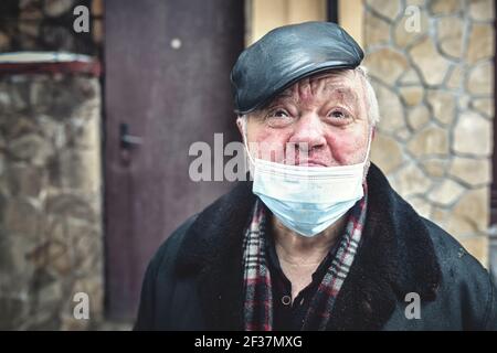 Kyiv. Ukraine - February 4: 2021 The cries of an injured homeless man wearing a protective mask, looking into a camera, feeling depressed in quarantin Stock Photo