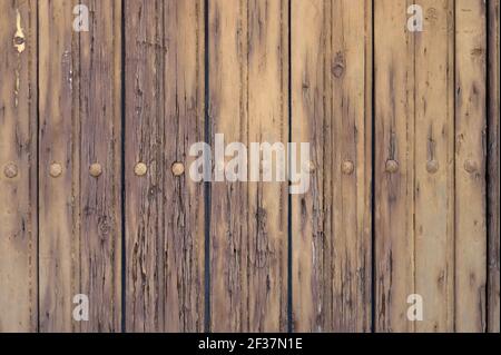 detail of an old wooden door painted in beige with nails Stock Photo