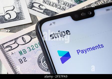 Stripe Payment provider website seen on the corner of smartphone placed on the dollar bills. Stafford, United Kingdom, March 14, 2021. Stock Photo