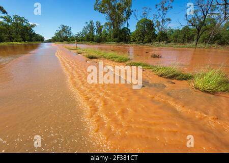 Remote Outback road flooded and covered in red mud after a storm, near Thallon, Queensland, QLD, Australia Stock Photo