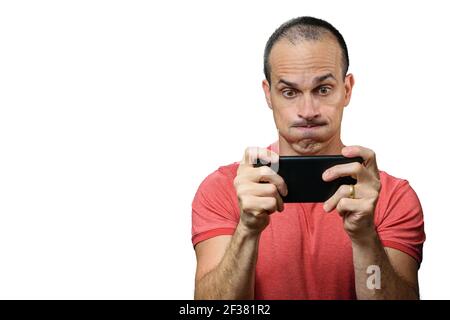 Mature man in casual clothes playing on the smartphone and making a funny face. Stock Photo
