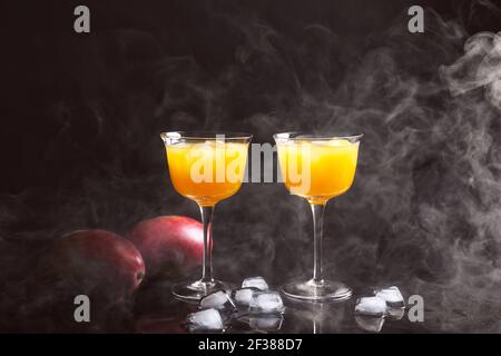 Glasses of tasty mango margarita on dark background Stock Photo