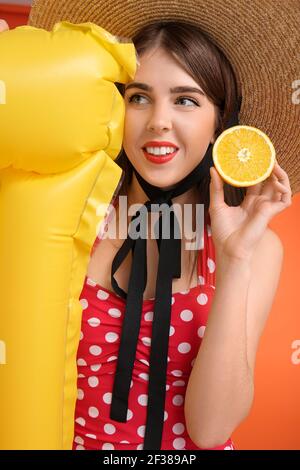 Beautiful young woman with orange and inflatable mattress on color background, closeup Stock Photo