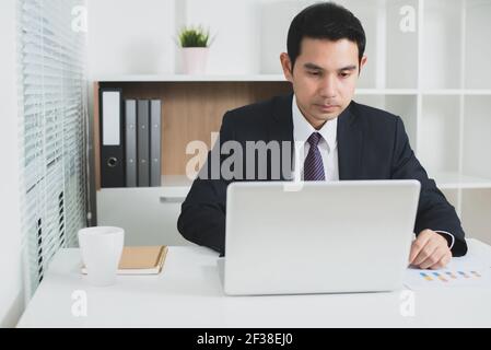 Asian businessman concentrating on using laptop computer in the office  - soft tone Stock Photo