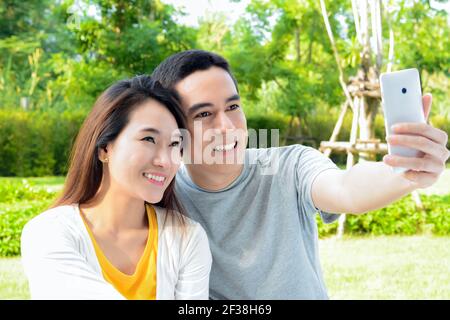 Young Asian couple taking selfie in the park Stock Photo